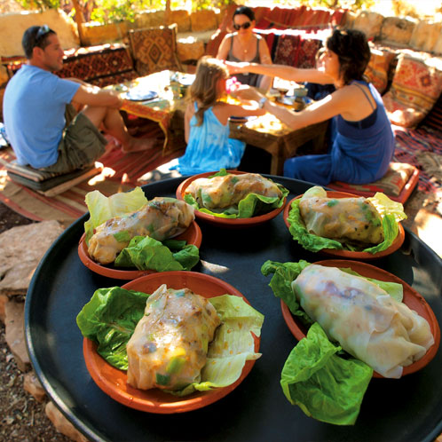 Guests being served under a carob tree at Goats with the Wind restaurant - Galilee, Israel. Photography by Tal Gluck.